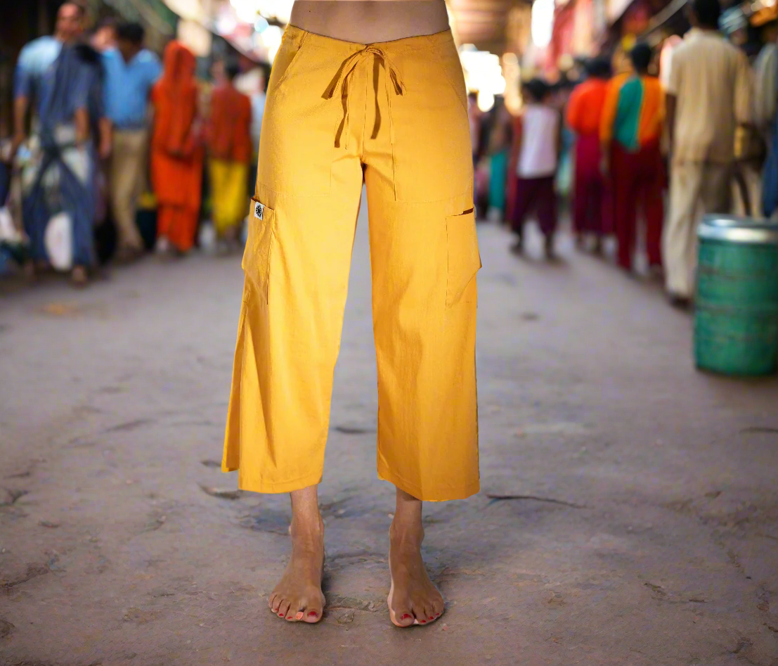 woman standing in an Indian street wearing an eco-friendly Tumeric yellow Serenity Pant in sustainable Tencel fabric — 22" cropped wide-leg yoga pants