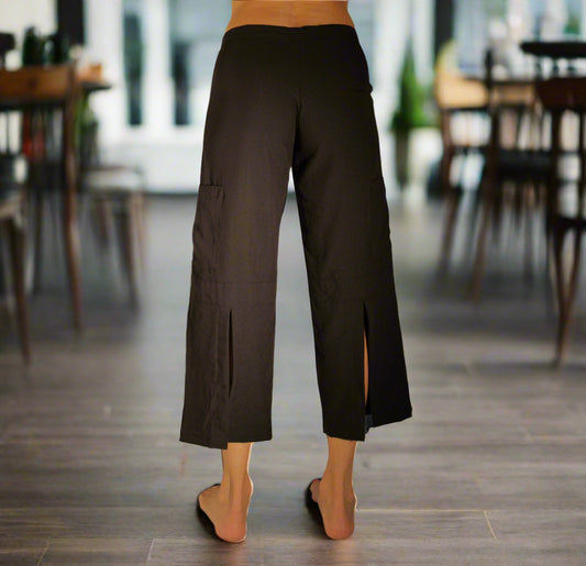 Woman in a cafe wearing an eco-friendly Black Serenity Pant in sustainable Tencel fabric — 22" cropped wide-leg yoga pants.  Rear view of a cute butt and sexy slits down the back of the pants